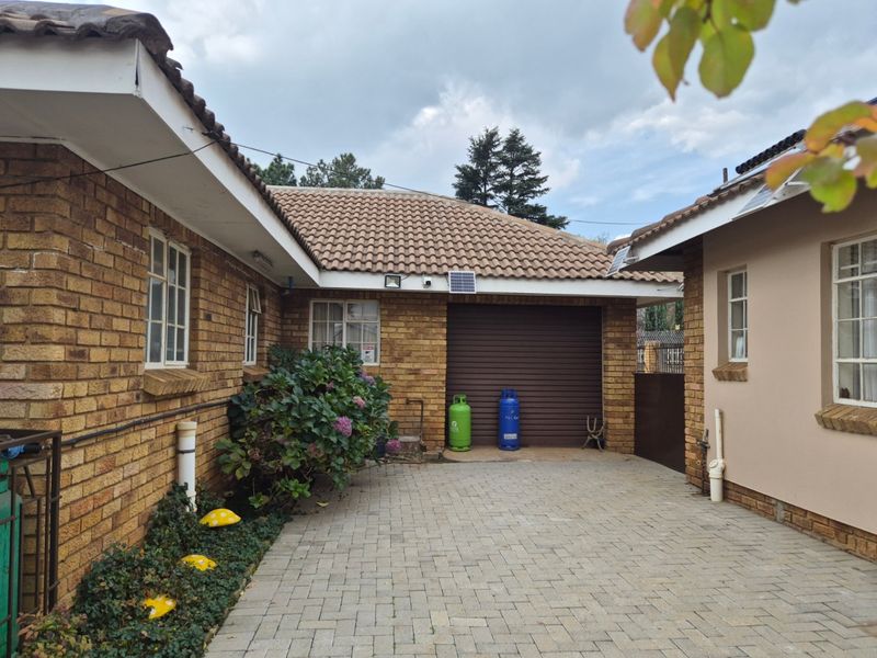 A paved rear courtyard area featuring brick exterior walls, a tiled roof, and a secure roller garage door.