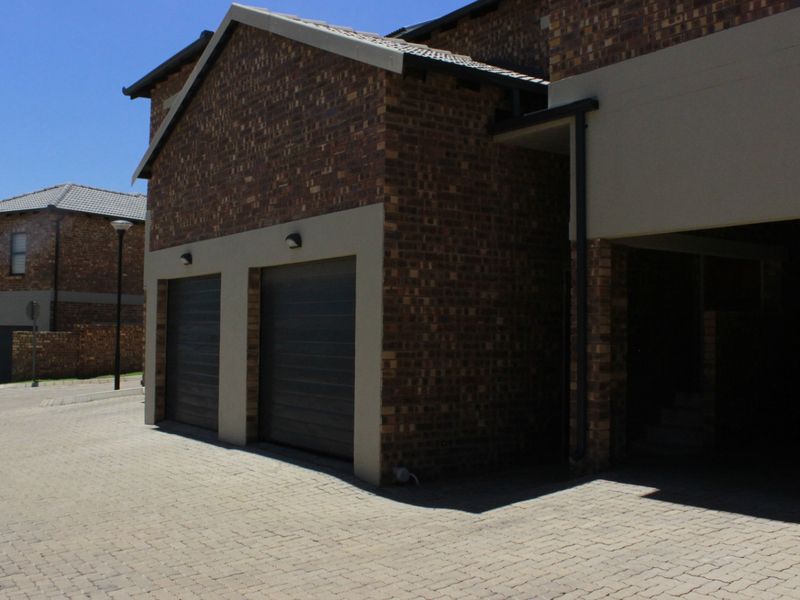 Front view of a modern double-story house featuring a double garage, brick exterior, and a paved driveway in a residential estate setting.