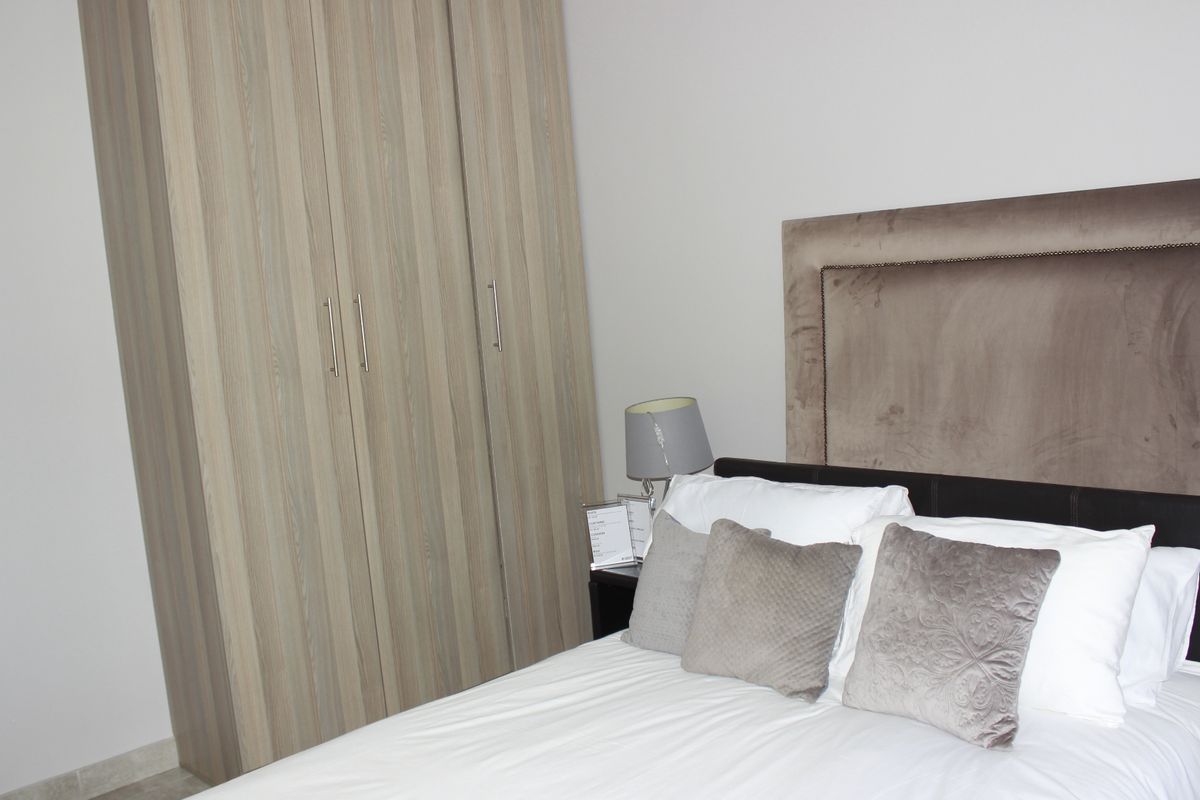 A well-maintained bedroom featuring a modern built-in wardrobe with wood-grain finish.