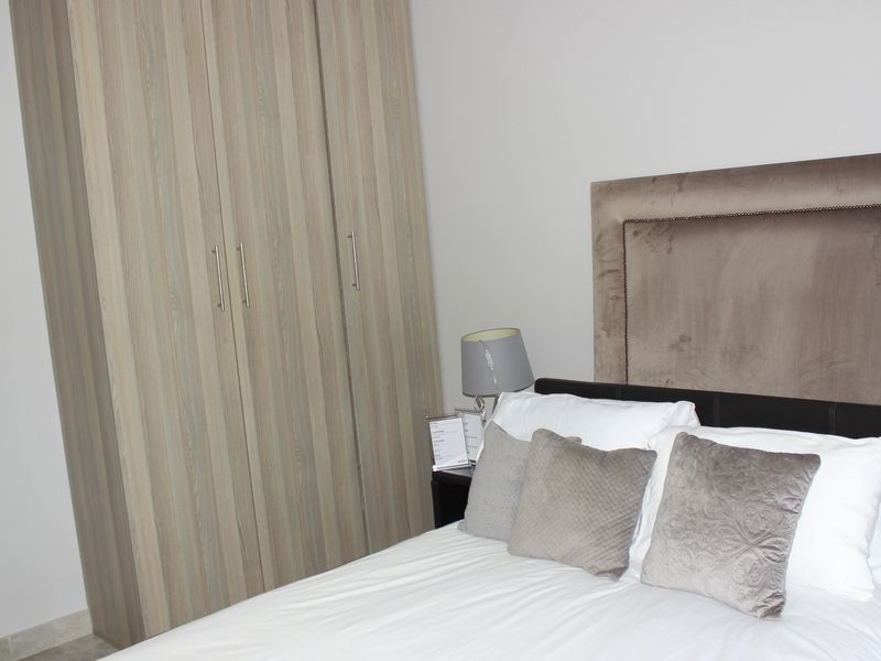 A well-maintained bedroom featuring a modern built-in wardrobe with wood-grain finish.