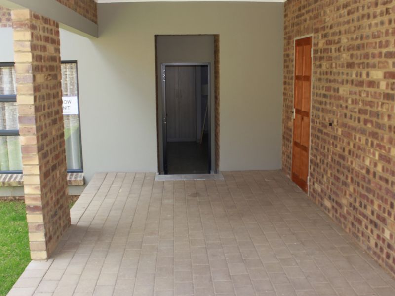 A covered patio area featuring paved flooring, exposed brick walls, and brick pillars, providing a functional outdoor transition space.