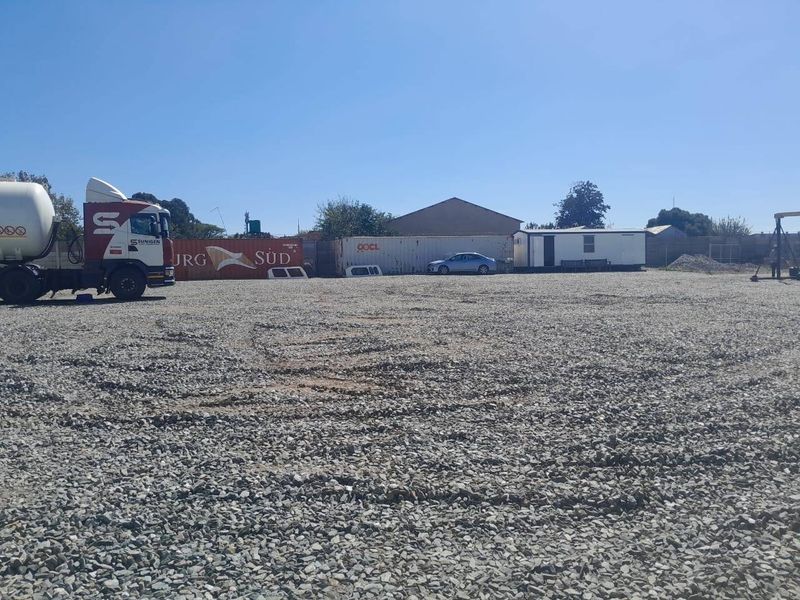 A large, open commercial yard area featuring a gravel surface, suitable for storage or industrial use.