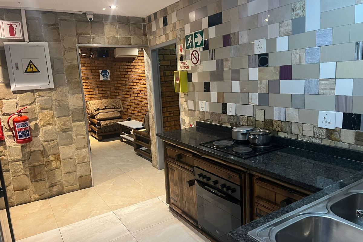 Kitchen area featuring granite countertops, built-in oven and hob, and decorative stone and mosaic tile wall finishes.