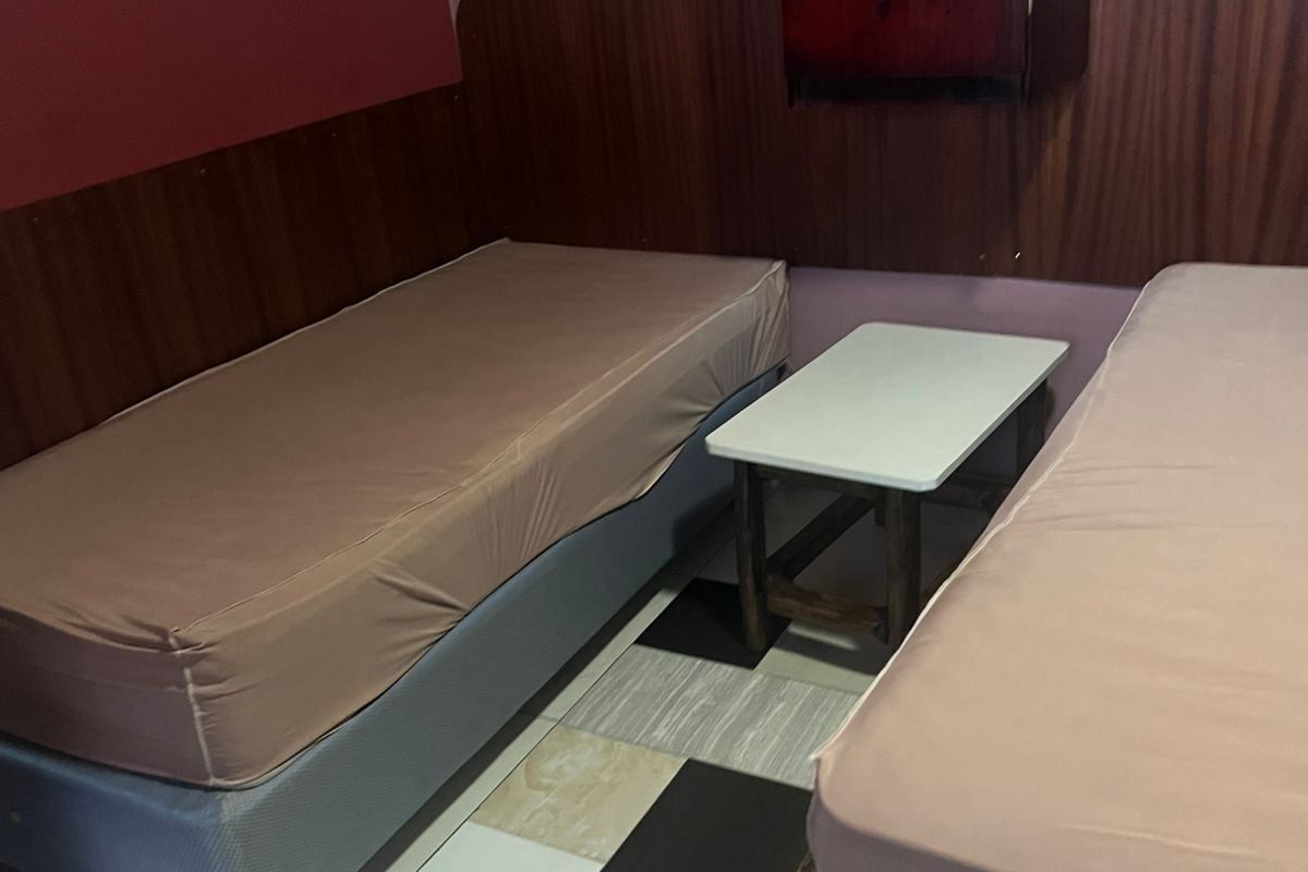 A bedroom featuring wood-panelled wall accents and tiled flooring, providing a functional sleeping space.