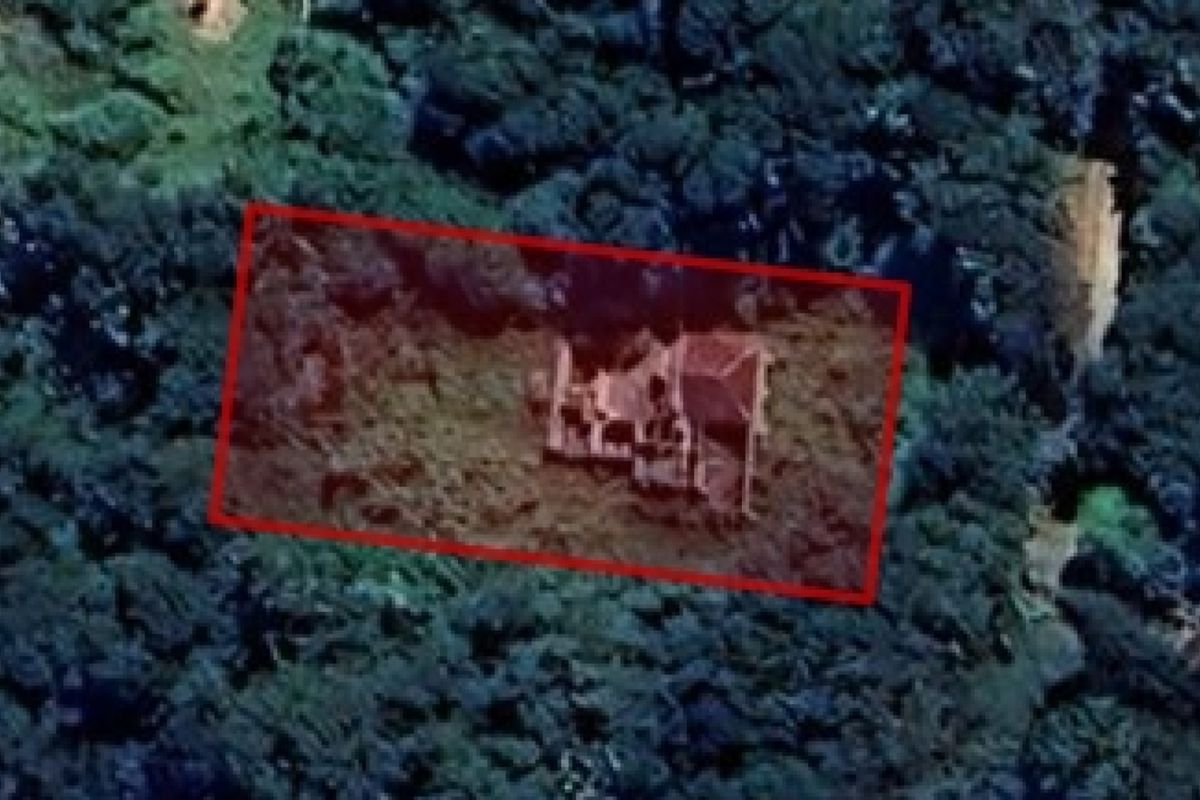 An aerial view of a vacant residential plot surrounded by dense vegetation, highlighting the property boundaries.
