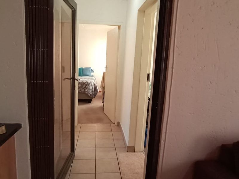 A functional hallway connecting living areas to bedrooms, featuring tiled flooring and secure internal access points.