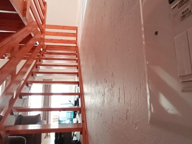 Interior view of a wooden staircase leading to an upper level, featuring a wall-mounted electrical distribution board.