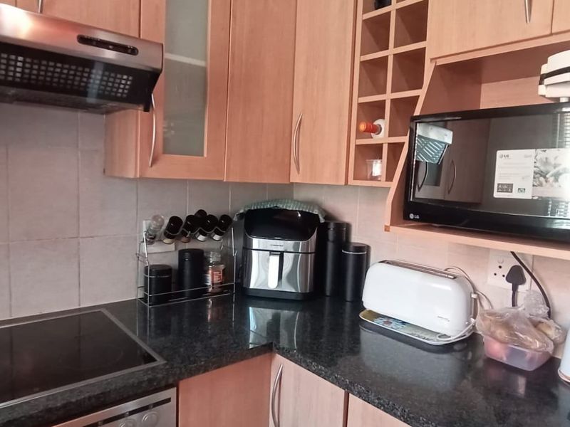 A functional kitchen featuring laminate cabinetry, granite countertops, a built-in hob, and an extractor fan with tiled splashbacks.