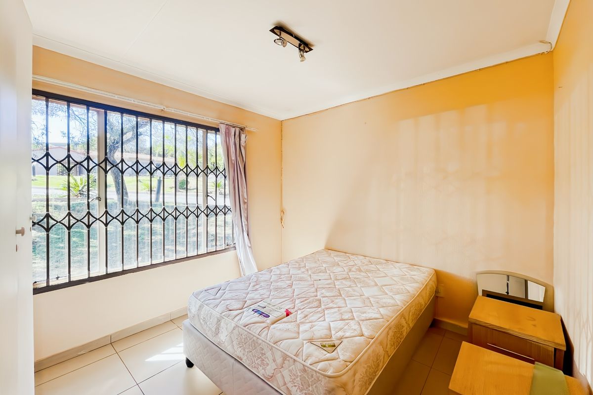 A bedroom featuring tiled flooring and a security gate on the window. The walls show signs of wear and require cosmetic attention.