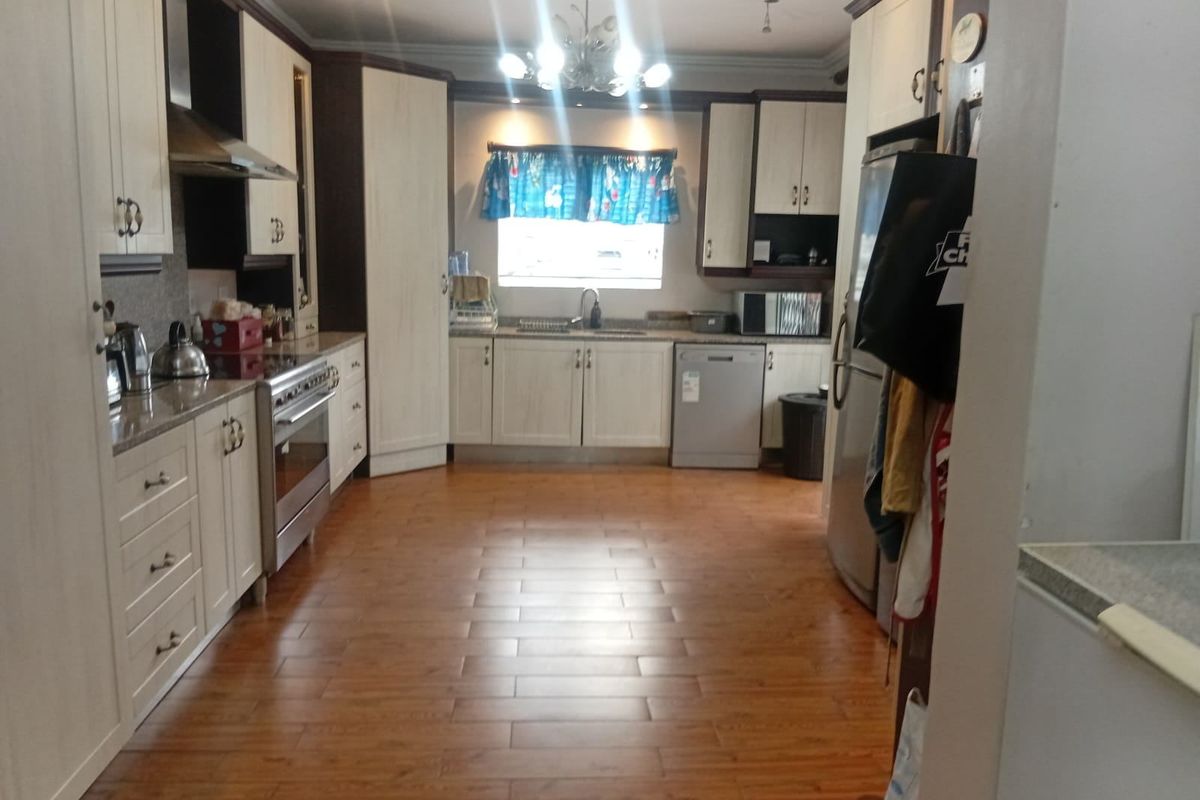 A functional kitchen featuring light-toned cabinetry, stainless steel appliances, and wood-look laminate flooring, providing ample storage and workspace.