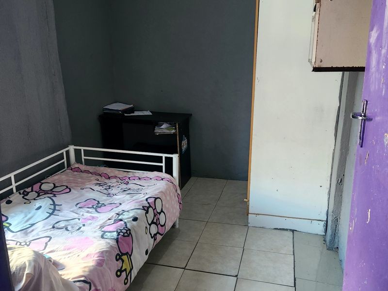 A compact bedroom featuring tiled flooring, a built-in cupboard, and a ventilation grille, requiring cosmetic updates to improve the overall finish and appeal.