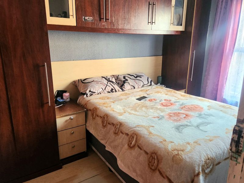 A bedroom featuring extensive built-in dark wood cabinetry, overhead storage units, and integrated bedside drawers, providing ample storage space.