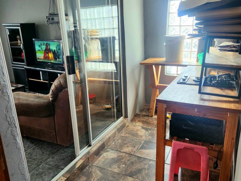 A living area featuring tiled flooring, a sliding glass door, and decorative ceiling cornices, requiring cosmetic updates to improve the overall aesthetic.
