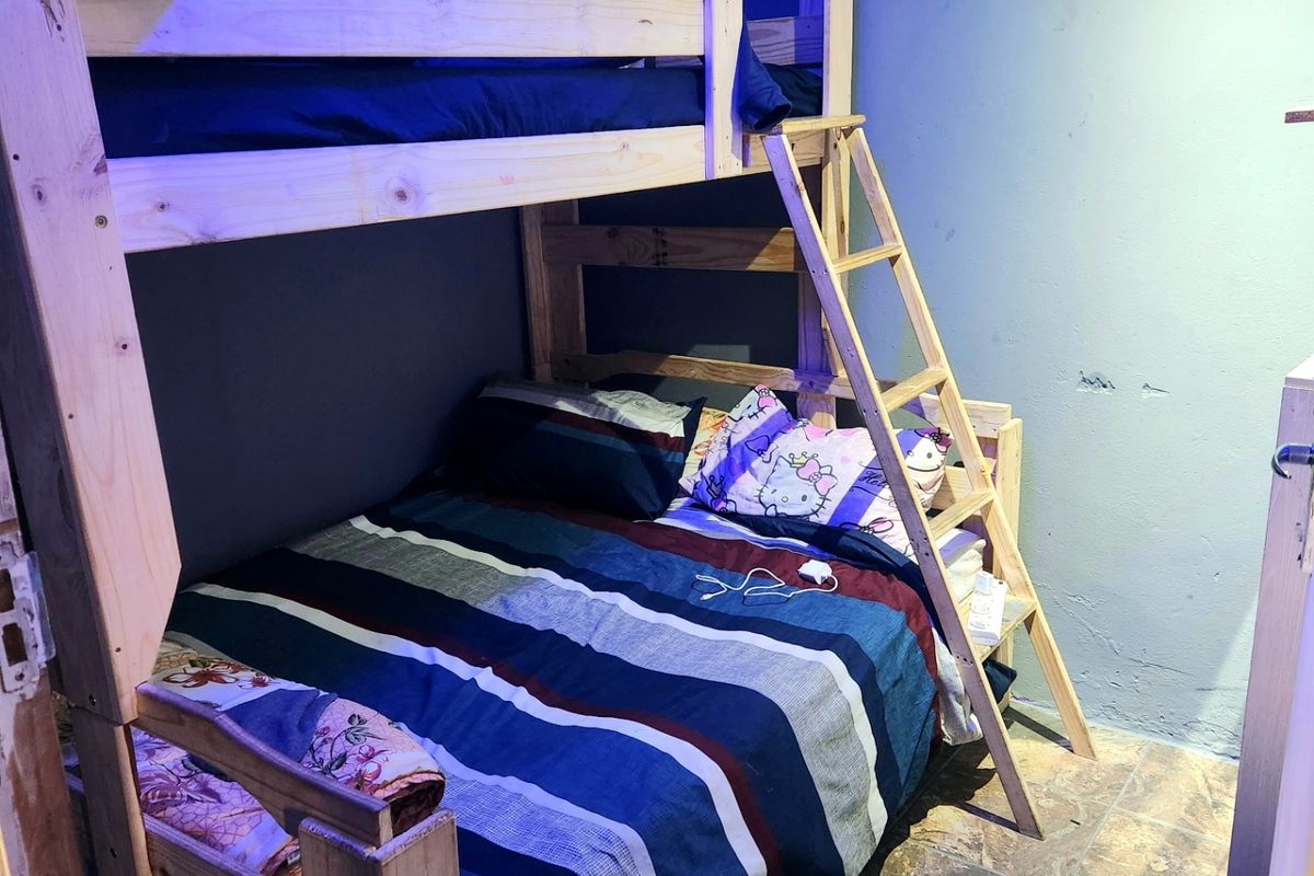 A bedroom featuring tiled flooring and decorative ceiling cornicing, currently showing signs of wall surface wear and requiring cosmetic attention.