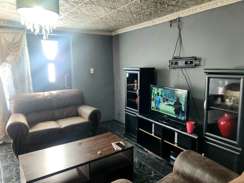 Living room featuring decorative ceiling tiles, tiled flooring, and coving, requiring cosmetic updates to address wall cracks and exposed wiring.