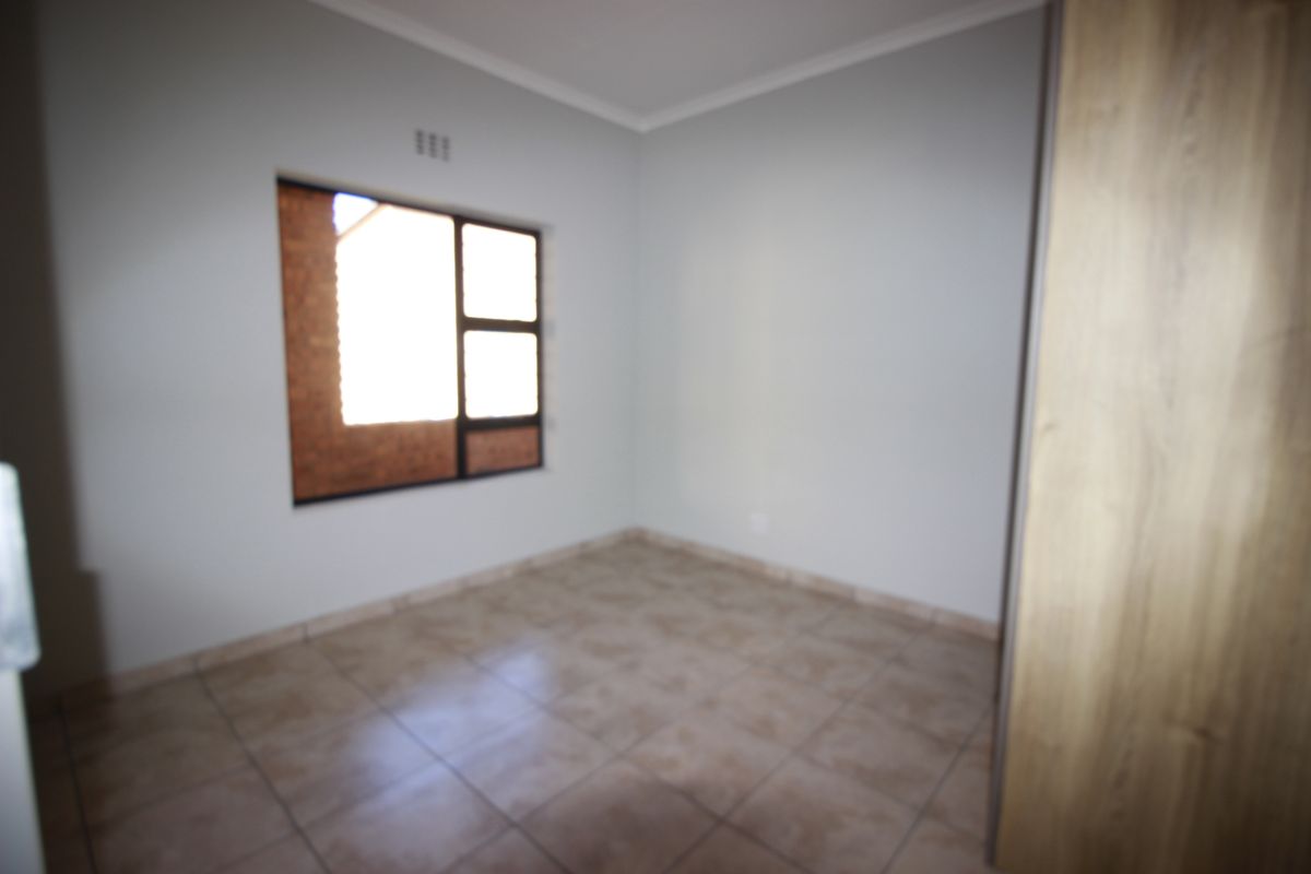 An empty bedroom featuring tiled flooring and a built-in cupboard, providing a clean and neutral space ready for personalization.