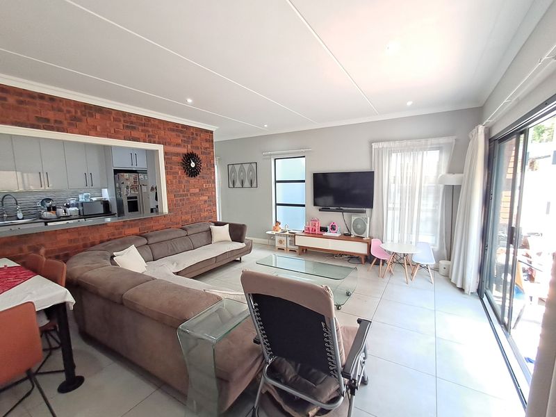 Open-plan living area featuring a brick feature wall, tiled flooring, and large sliding glass doors leading to an outdoor space.