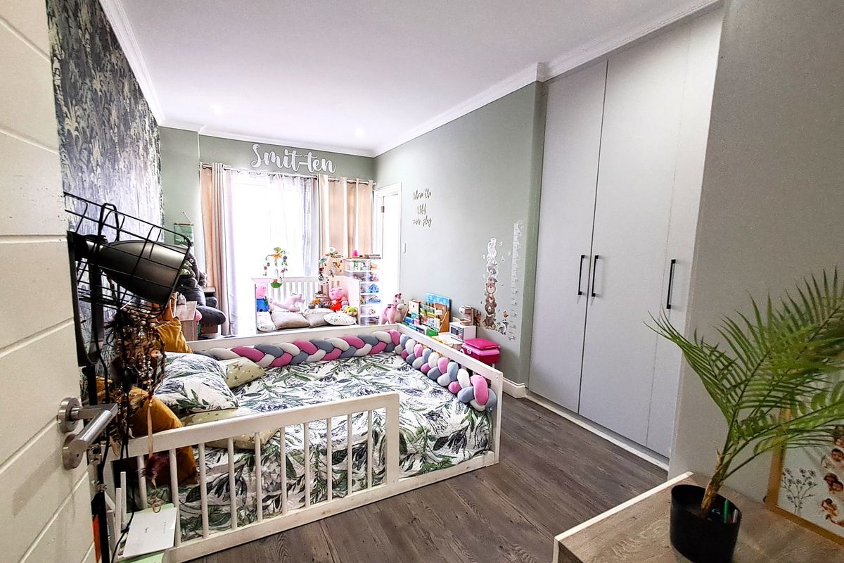 A well-maintained bedroom featuring built-in floor-to-ceiling wardrobes, laminate wood flooring, and decorative wallpaper, offering a functional and comfortable living space.