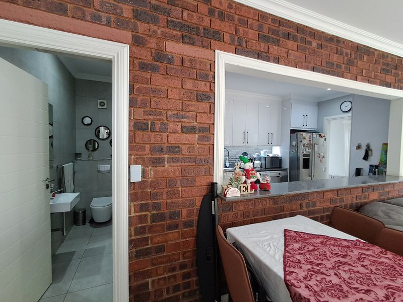 View through to a modern kitchen with white cabinetry and a separate bathroom featuring contemporary fixtures and tiled finishes.