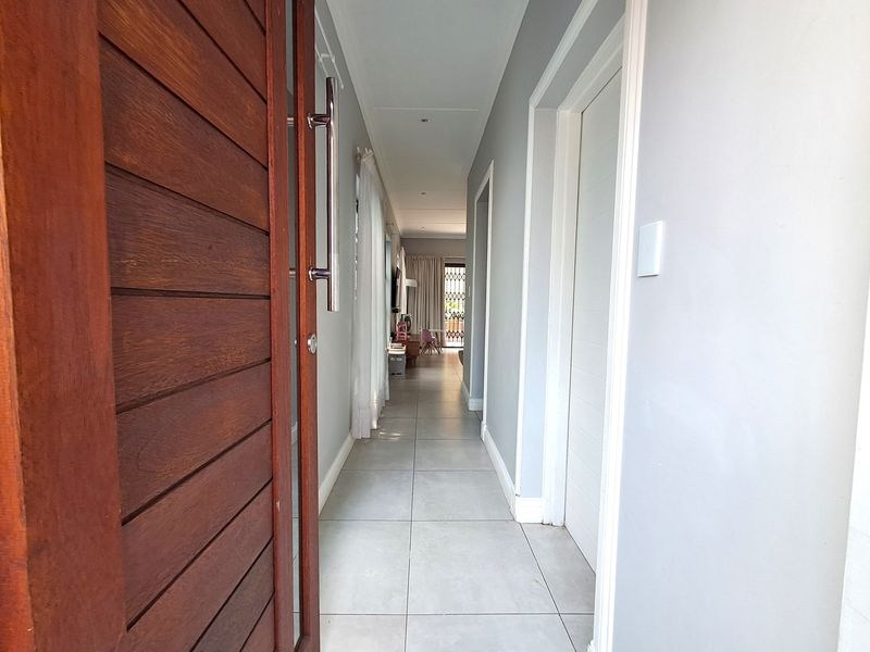 A bright entrance hallway featuring tiled flooring and a solid timber front door, leading through to the open-plan living area.