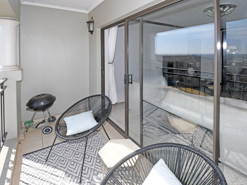 A covered balcony featuring tiled flooring, a metal balustrade, and large sliding glass doors providing access to the interior living space.