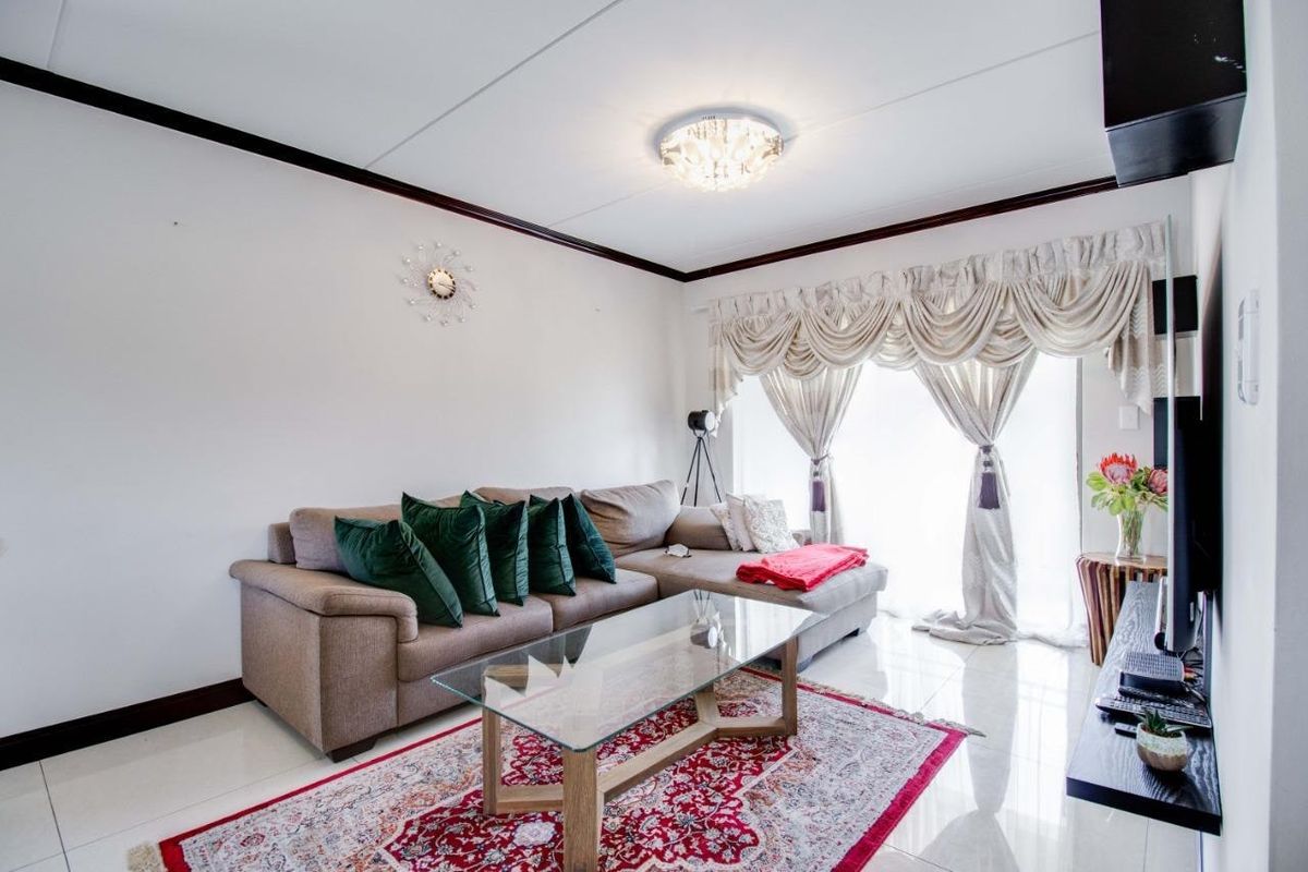 A bright living room featuring polished tiled flooring and a sliding glass door providing access to the exterior.