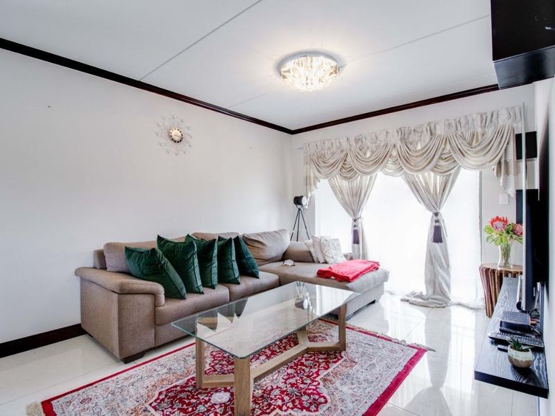 A bright living room featuring polished tiled flooring and a sliding glass door providing access to the exterior.