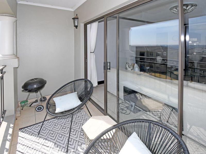 A covered balcony featuring tiled flooring, a wrought iron railing, and large sliding glass doors providing access to the interior living space.