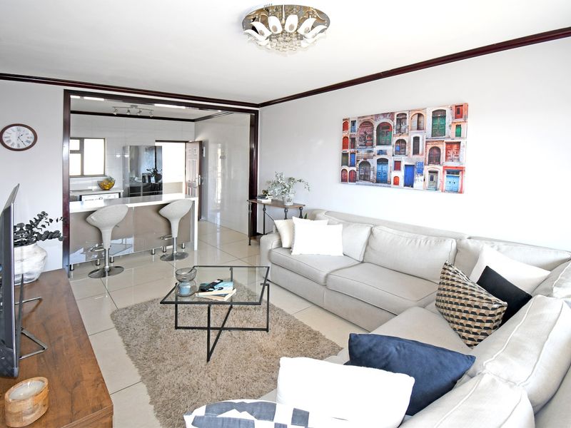An open-plan living area featuring tiled flooring, a breakfast bar, and a seamless transition into the kitchen space.
