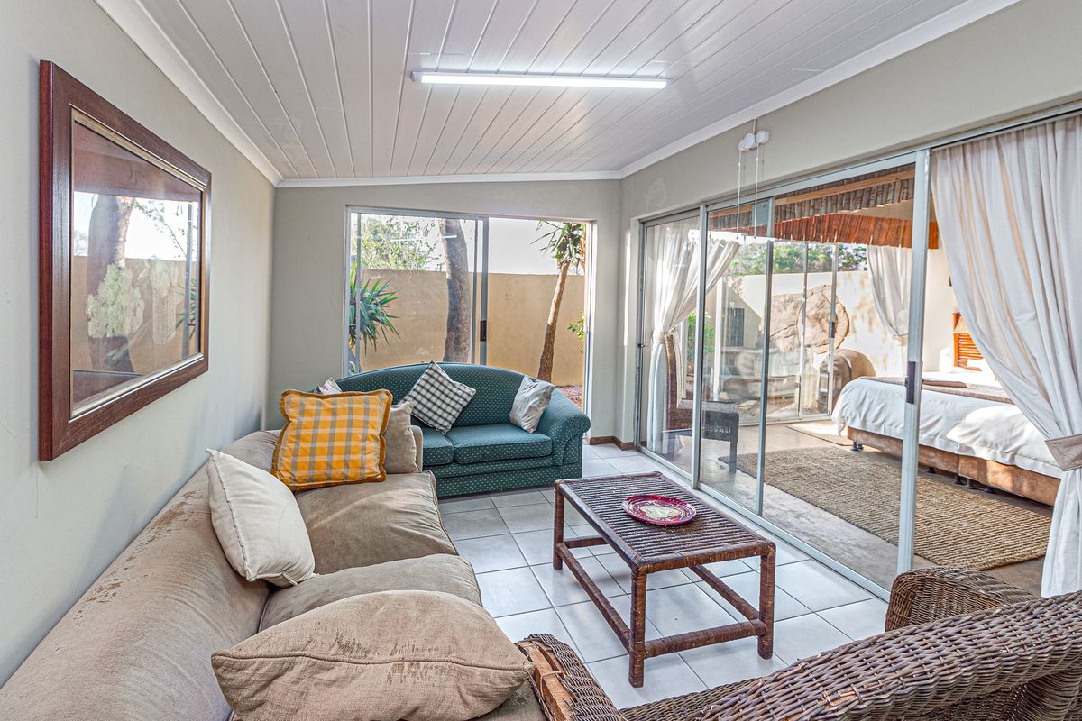 A sunroom or living area featuring tiled floors, tongue and groove ceiling, and large sliding glass doors providing access to an adjacent bedroom area.