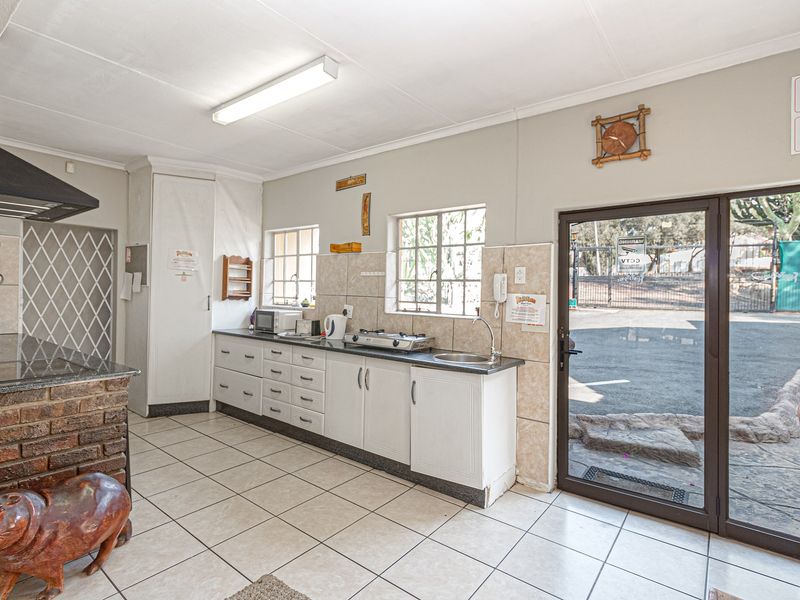 Functional kitchen featuring built-in cabinetry, granite countertops, tiled flooring, and direct access to the exterior through a glass door.