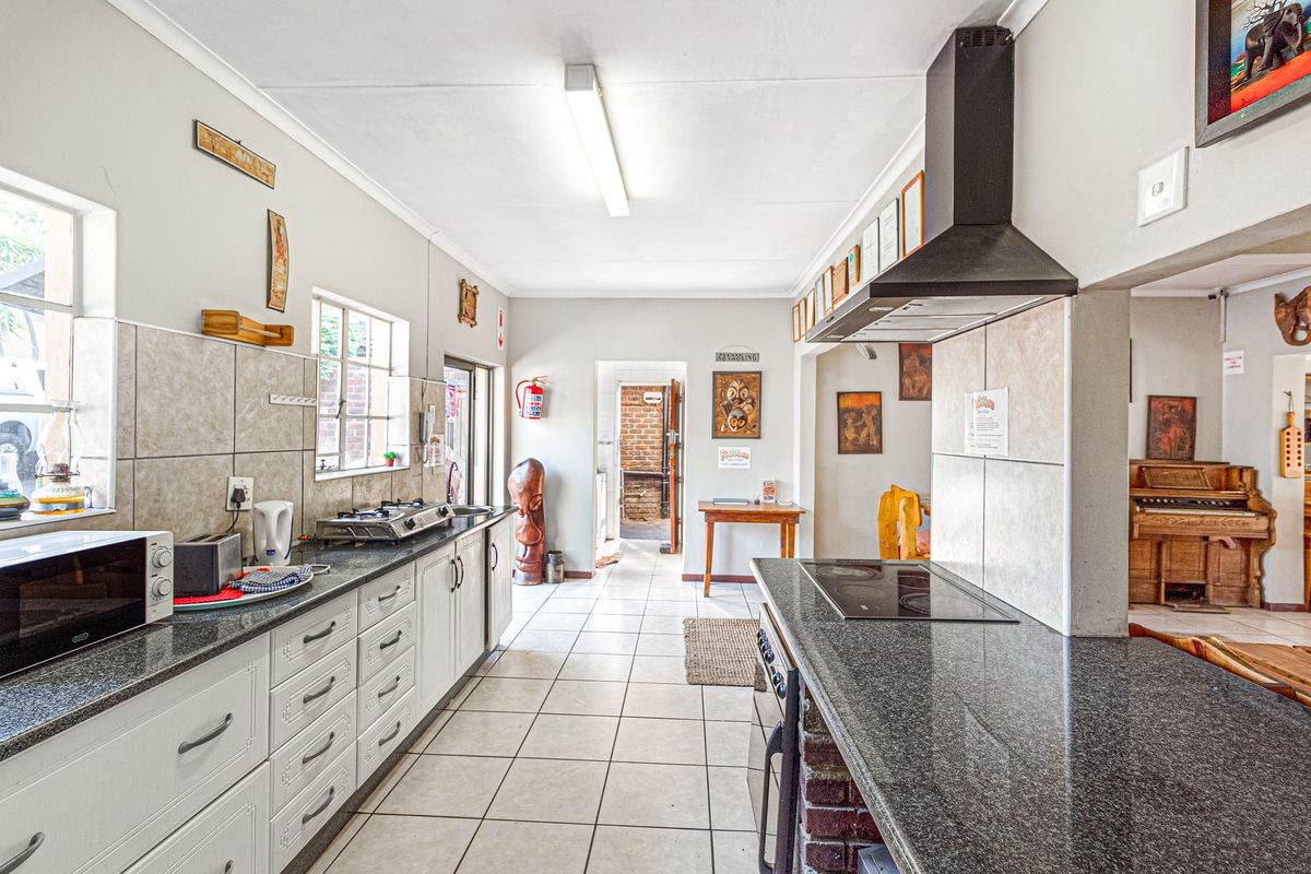 Spacious kitchen featuring granite countertops, dual cooking stations with a gas cooktop and electric hob, extractor fan, and ample built-in cabinetry.