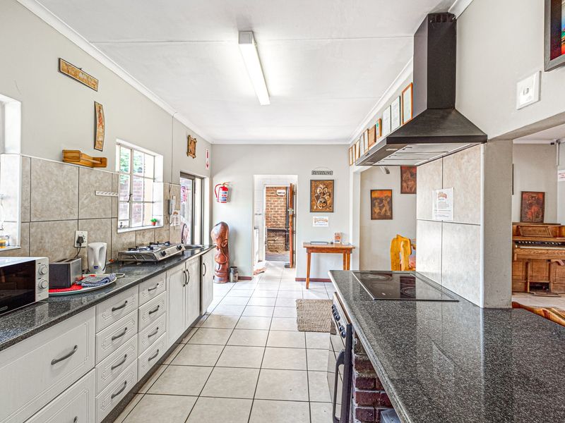 Spacious kitchen featuring granite countertops, dual cooking stations with a gas cooktop and electric hob, extractor fan, and ample built-in cabinetry.