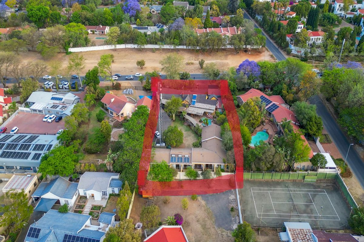Aerial view of a residential property featuring a main house, swimming pool, and established garden within a suburban neighborhood setting.