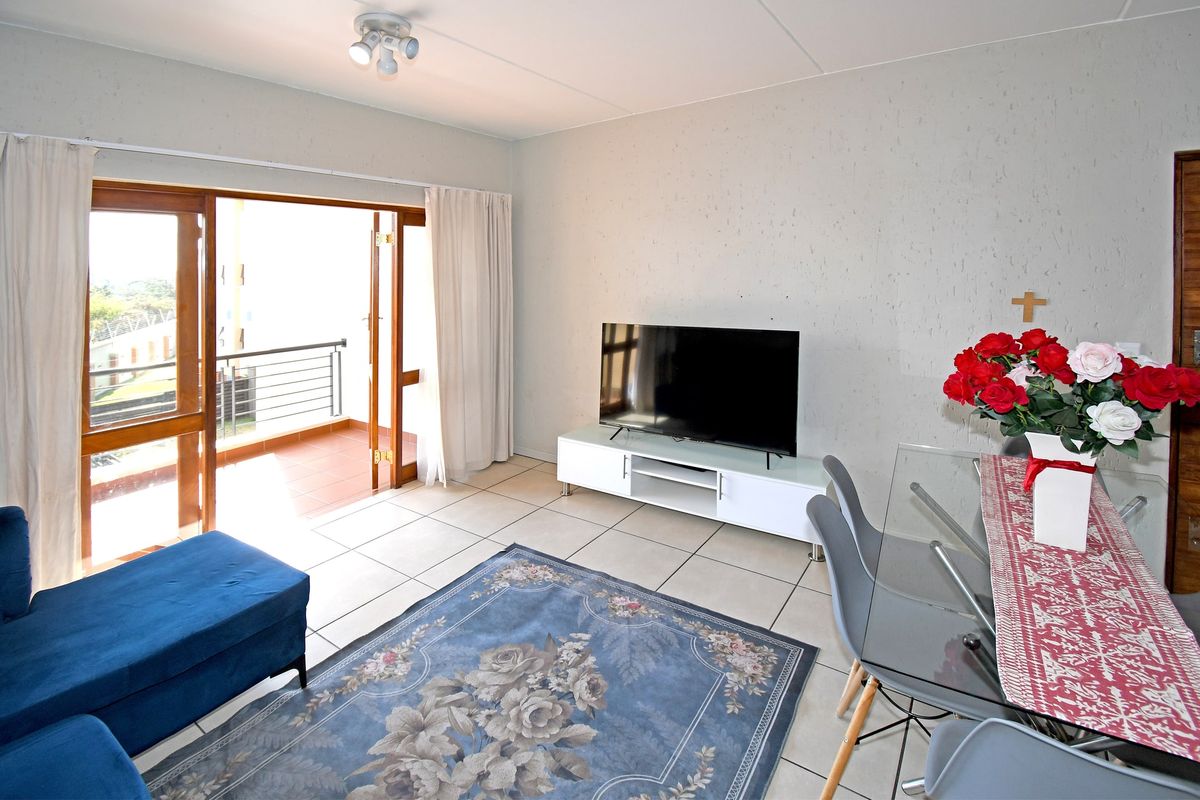 A living room featuring tiled flooring and direct access to a balcony through sliding glass doors, providing natural light to the space.
