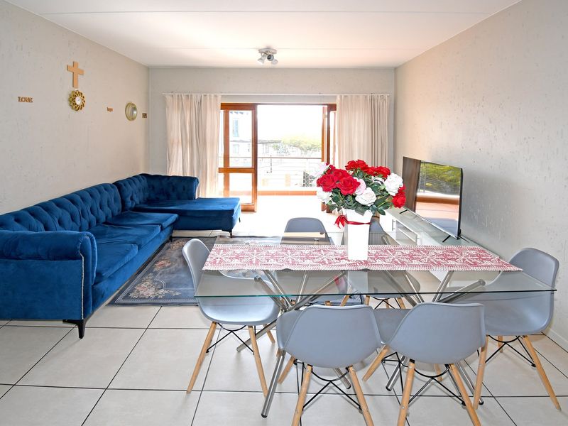 Open plan living and dining area featuring tiled flooring and a sliding glass door leading to an outdoor balcony.