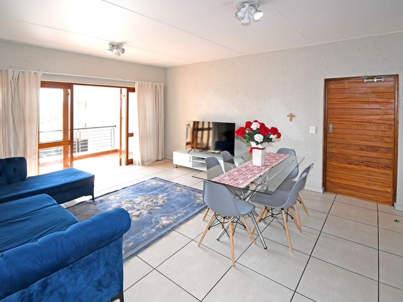 Spacious open-plan living and dining area featuring neutral tiled flooring and direct access to a private balcony through large sliding glass doors.