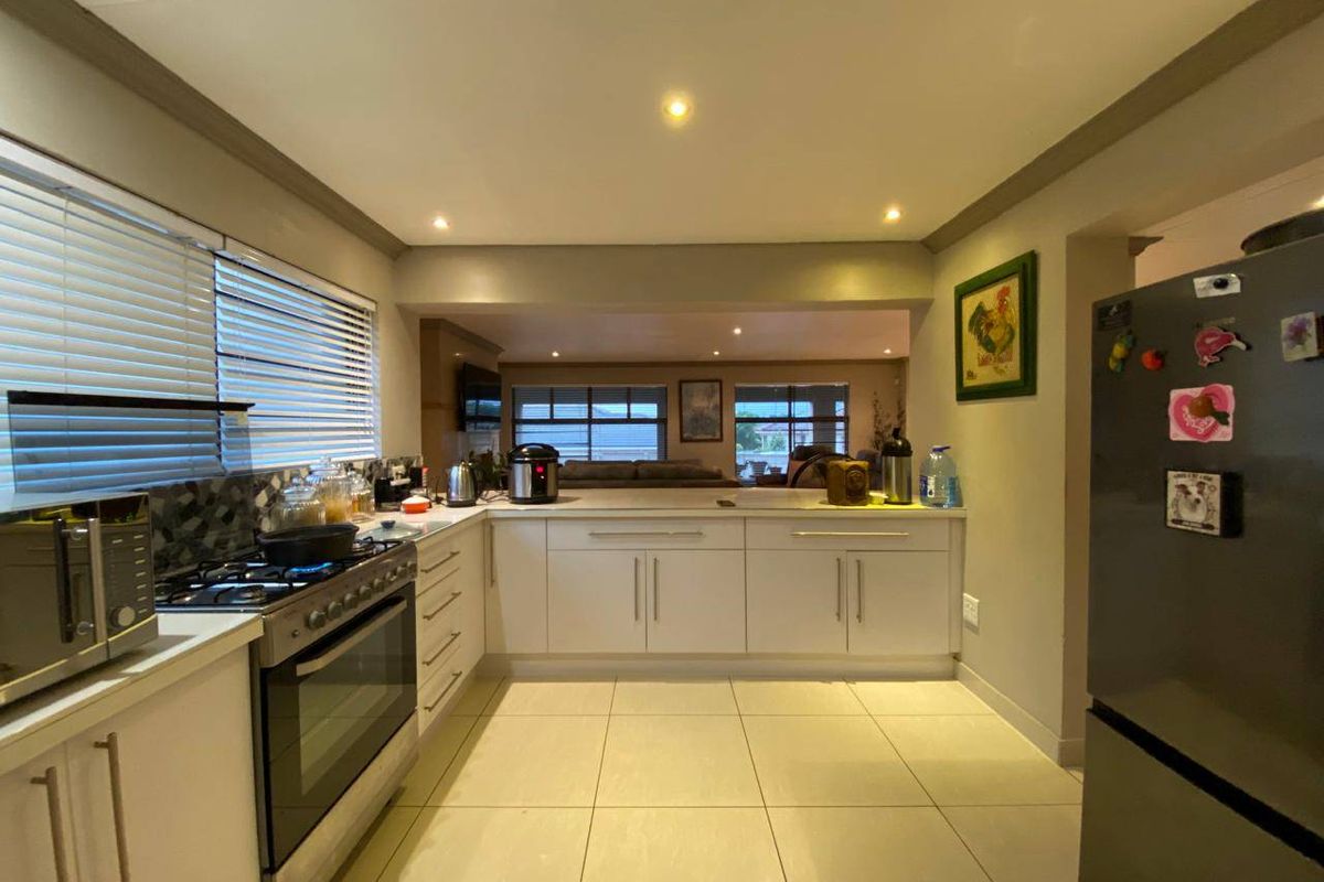 A functional kitchen featuring white cabinetry, a gas stove with extractor, tiled flooring, and recessed lighting, with an open-plan flow to the living area.