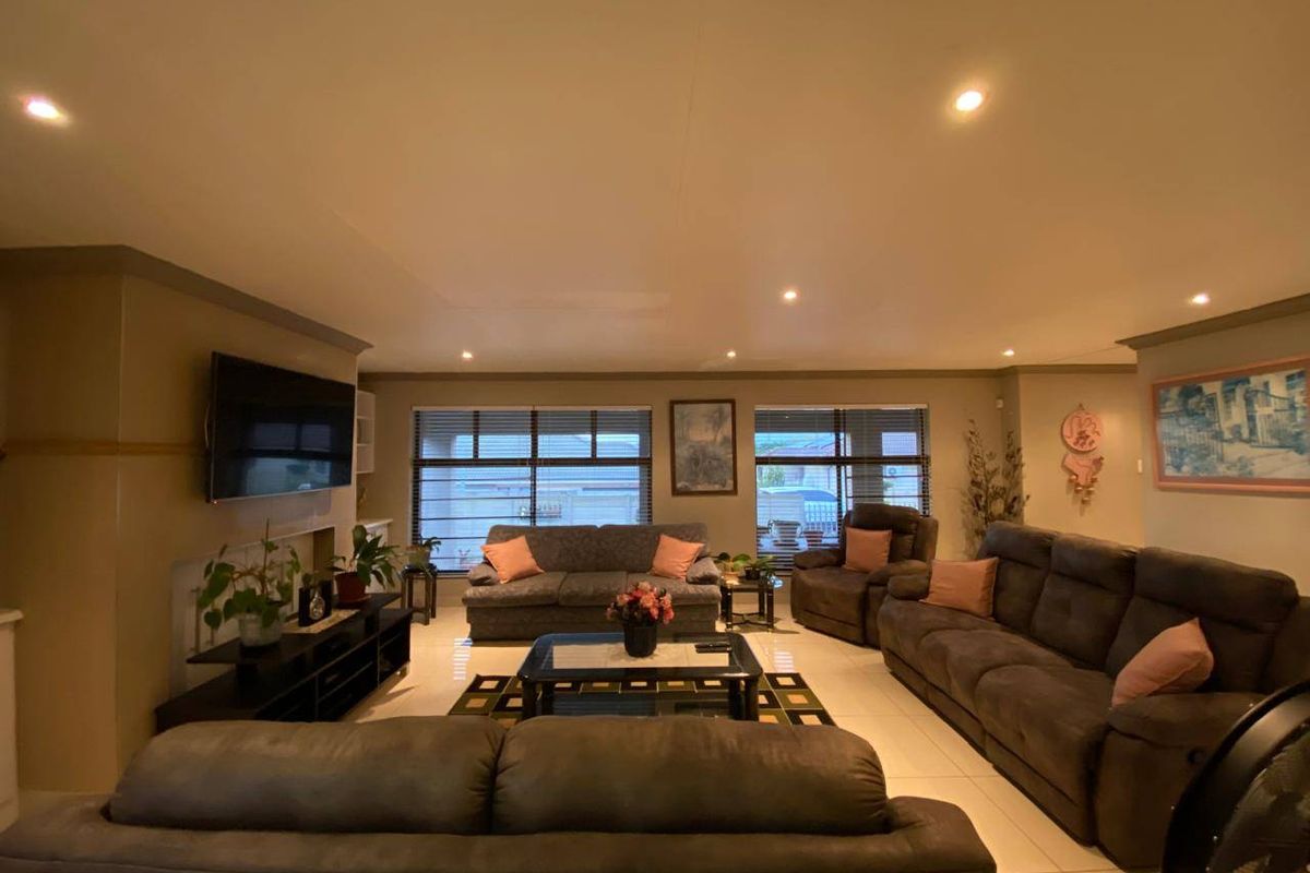 Spacious living room featuring tiled flooring, recessed downlighting, and large windows with venetian blinds, creating a comfortable and well-lit family area.