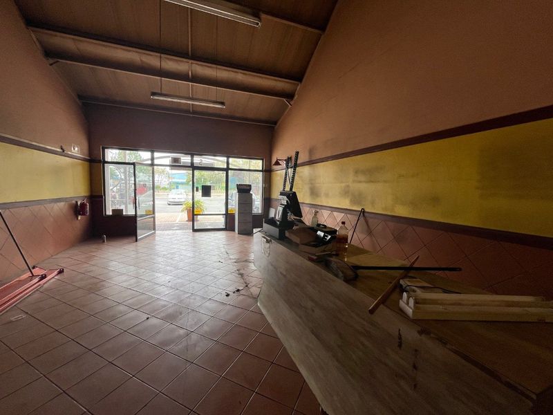 Commercial entry space featuring tiled flooring, a built-in service counter, and large glass entrance doors, offering a functional layout for retail or office use.