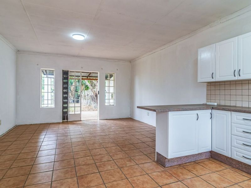 Open-plan living area featuring tiled flooring, a functional kitchen with built-in cabinetry and oven, and direct access to the outdoor patio area.