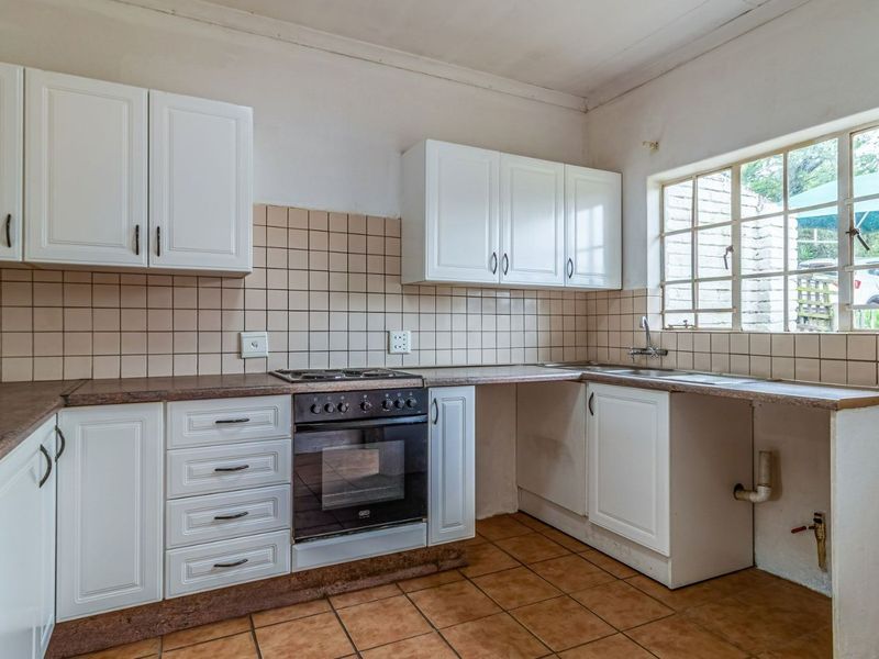 A functional kitchen featuring white cabinetry, a built-in oven with gas hob, tiled backsplash, and a stainless steel sink under a large window.