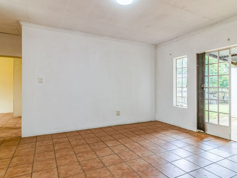 An empty living room featuring ceramic tile flooring, a coved ceiling, and a glass-paneled door providing direct access to the outdoor patio area.