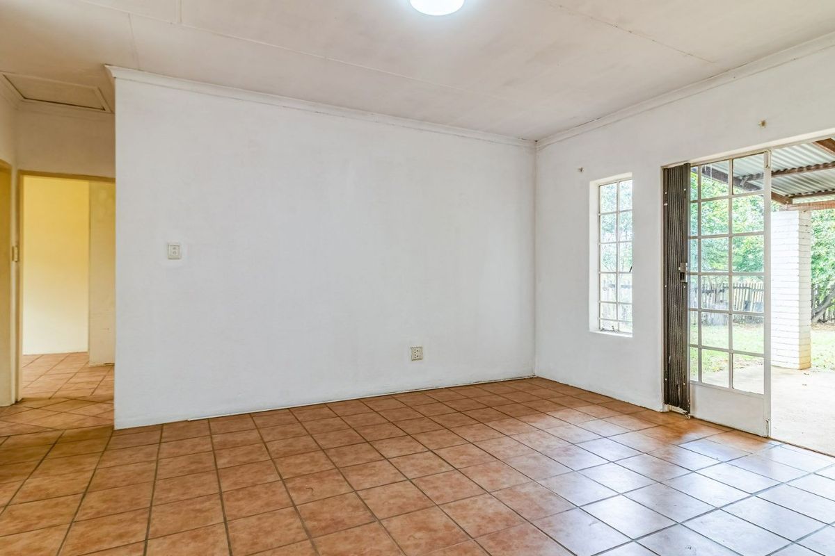 An empty living room featuring ceramic tile flooring, a coved ceiling, and a glass-paneled door providing direct access to the outdoor patio area.