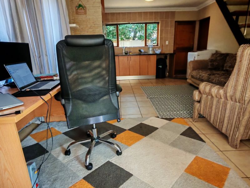 Open plan living area featuring tiled floors, a staircase, and a functional kitchen corner with built-in cabinetry and sink.