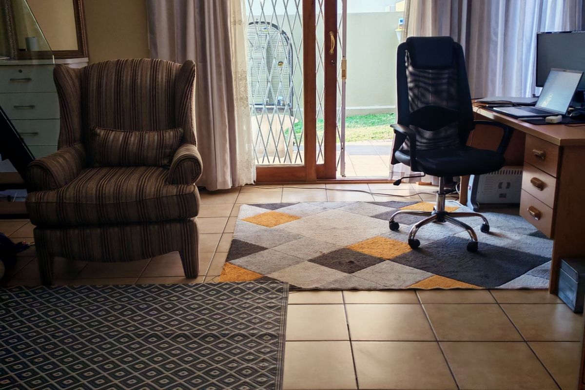 A living area featuring ceramic floor tiles and a sliding glass door with a security gate, providing direct access to the outdoor patio.