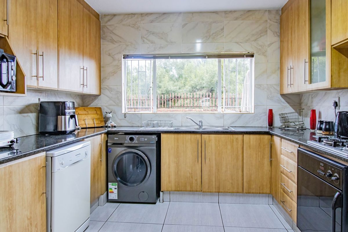 A well-maintained kitchen featuring light wood cabinetry, granite countertops, tiled backsplash, and integrated appliances including a gas hob and oven.