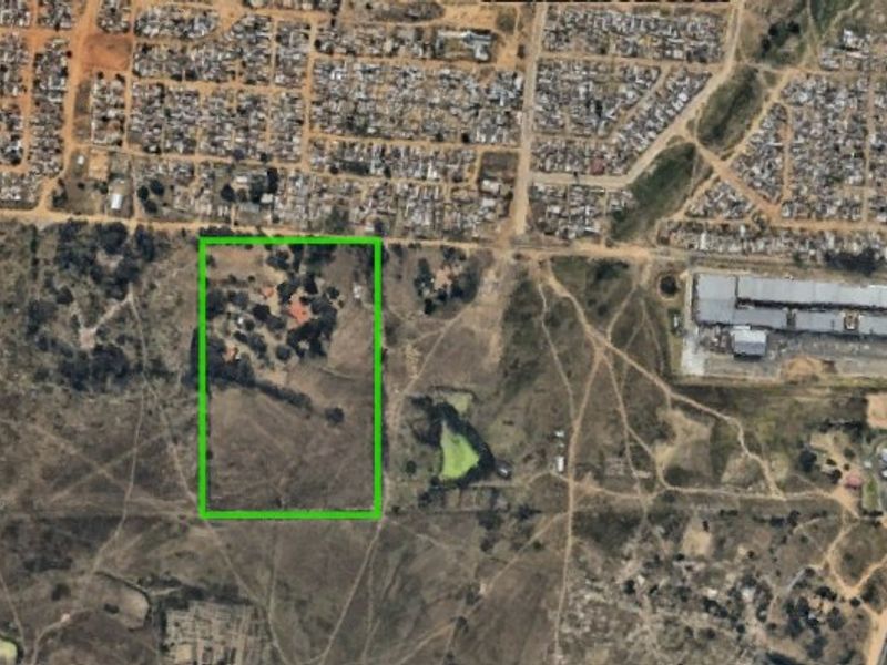Aerial view of a large farm property with a green boundary outline, showing surrounding landscape and nearby residential and commercial infrastructure.