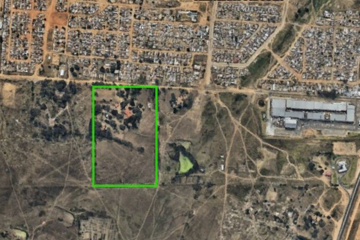 Aerial view of a large farm property with a green boundary outline, showing surrounding landscape and nearby residential and commercial infrastructure.
