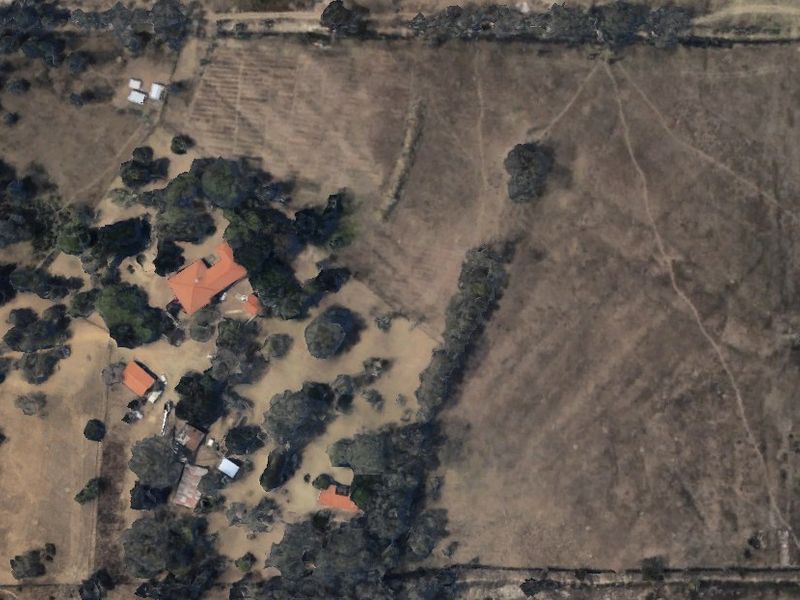 Aerial view of the farm property showing the main dwelling, outbuildings, surrounding land, and perimeter fencing.